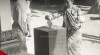Foto seorang ibu sambil menggendong bayinya sedang memasukkan surat suara ke dalam kotak suara di TPS Kemantren Wirogunan, Yogyakarta tanggal 29 September 1955.